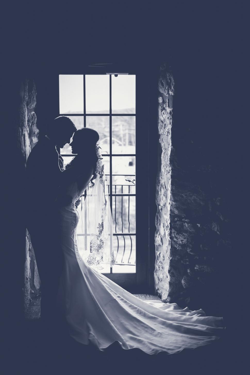 Free Image of A bride and groom kissing in front of a window 