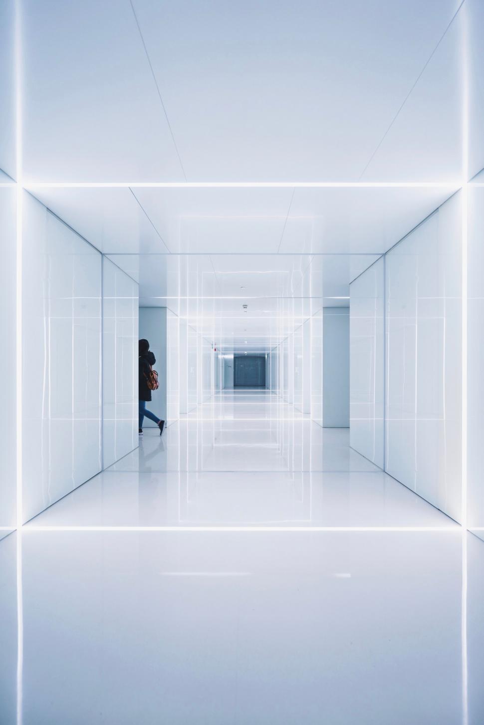 Free Image of A person walking in a white hallway 