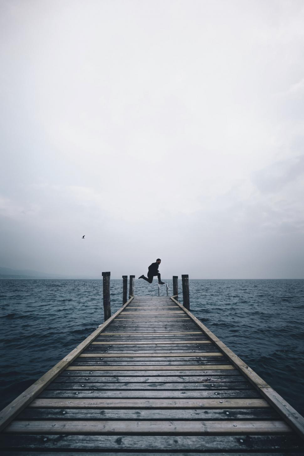 Free Image of A person jumping off a dock over water 