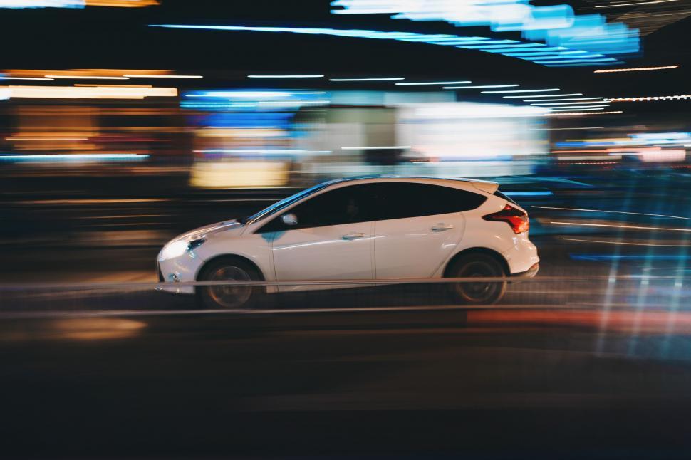 Free Image of A white car driving on a street at night 