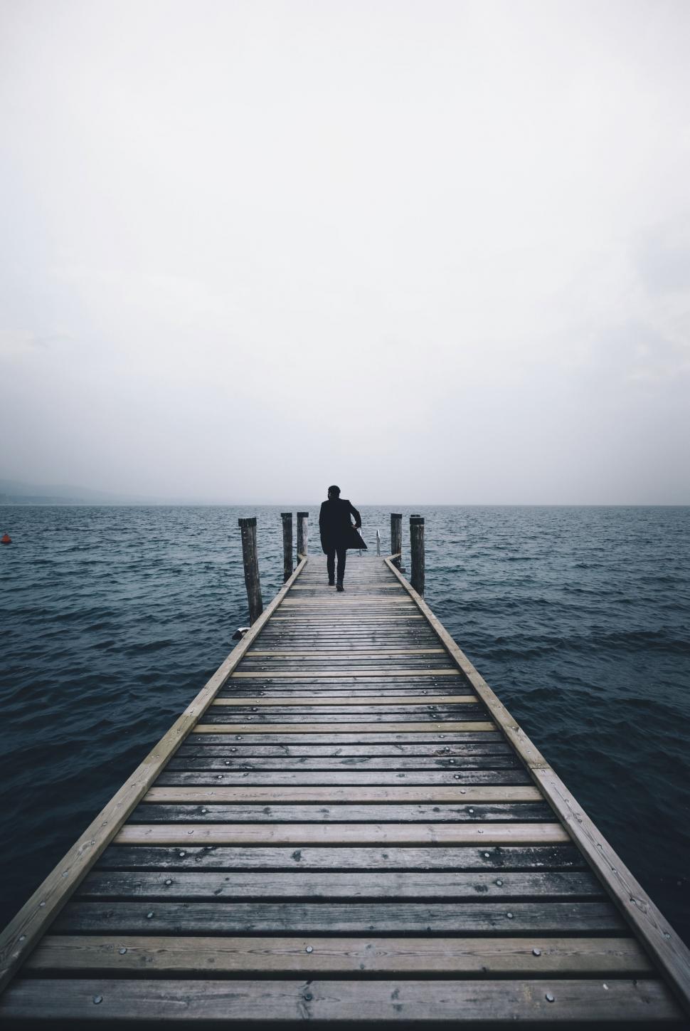 Free Image of A person walking on a dock over water 