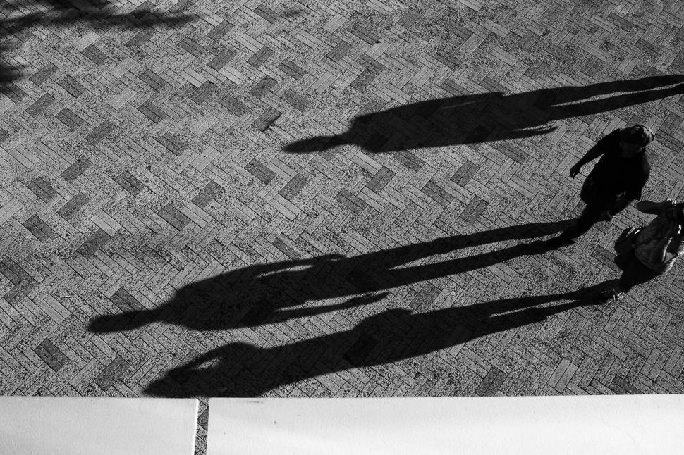 Free Image of Shadows of people on a brick walkway 
