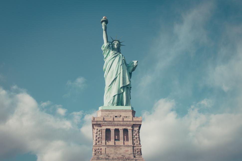 Free Image of A statue of liberty with clouds in the sky with statue of liberty in the background 