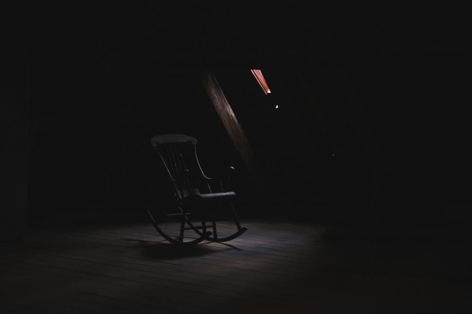 Free Image of A rocking chair in a dark room 