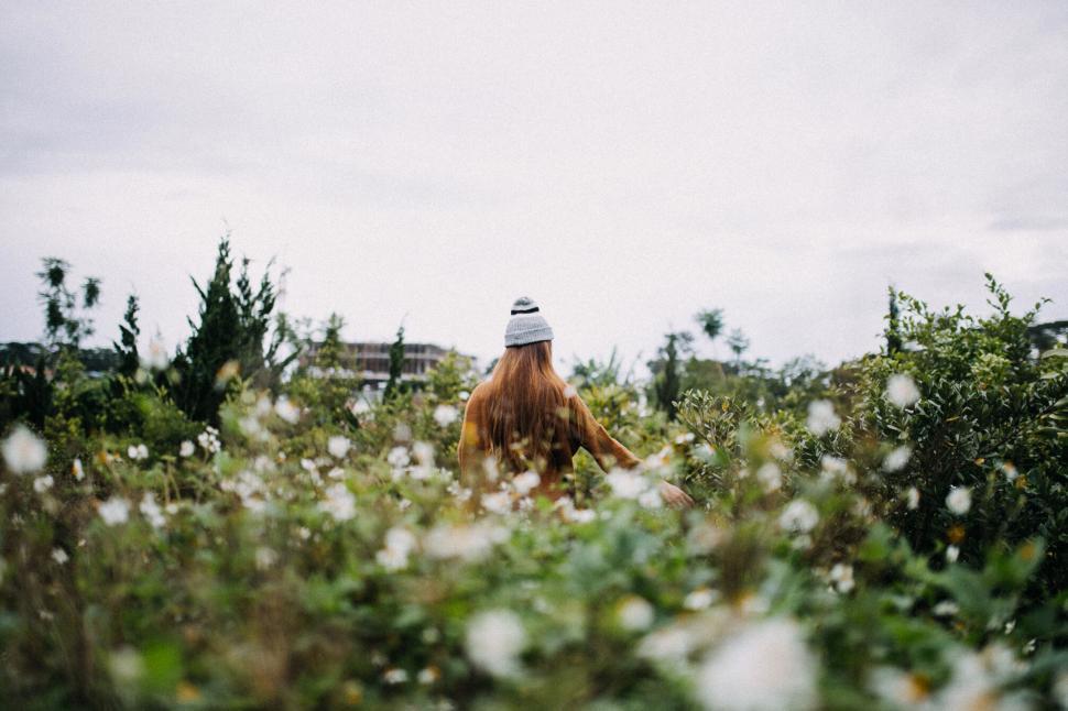 Free Image of A woman walking through a field of flowers 