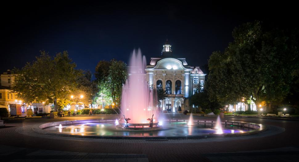 Free Image of A fountain in a park with a building in the background 
