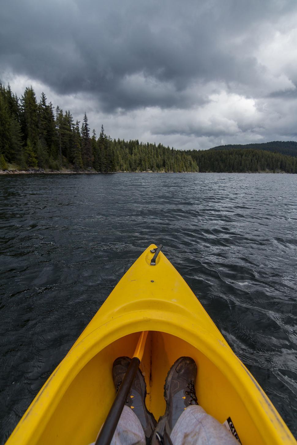 Free Image of A yellow kayak on a lake with trees in the background 