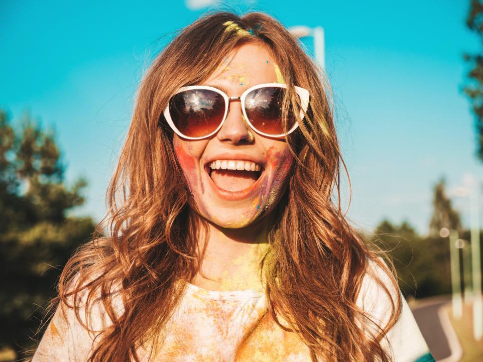 Free Image of A woman with sunglasses and paint on her face 