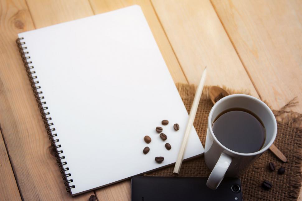 Free Image of A notebook and coffee beans and a pencil on a wood table 