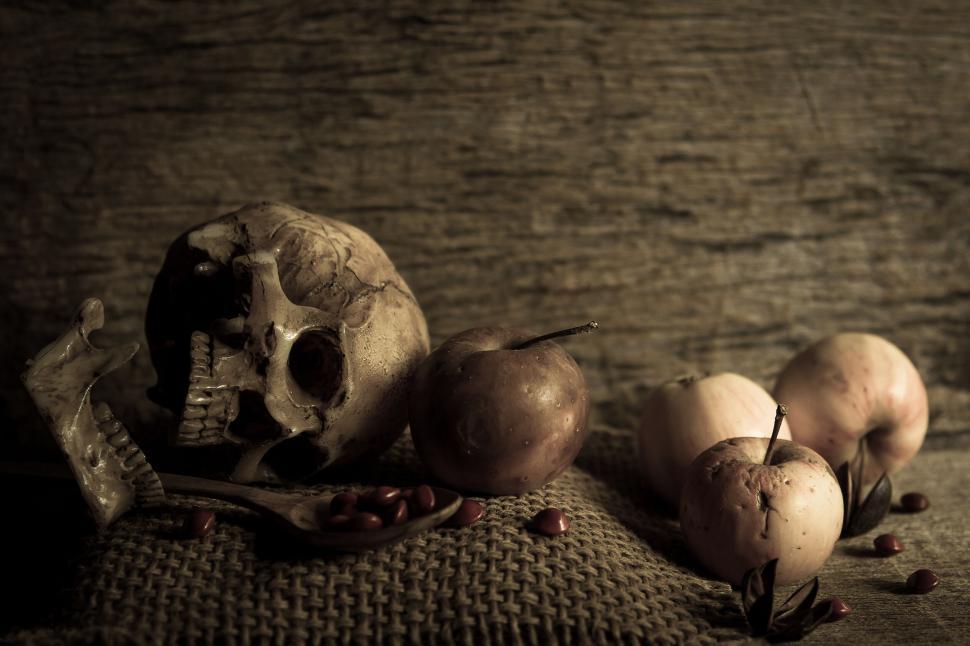 Free Image of A skull and apples on a burlap surface 