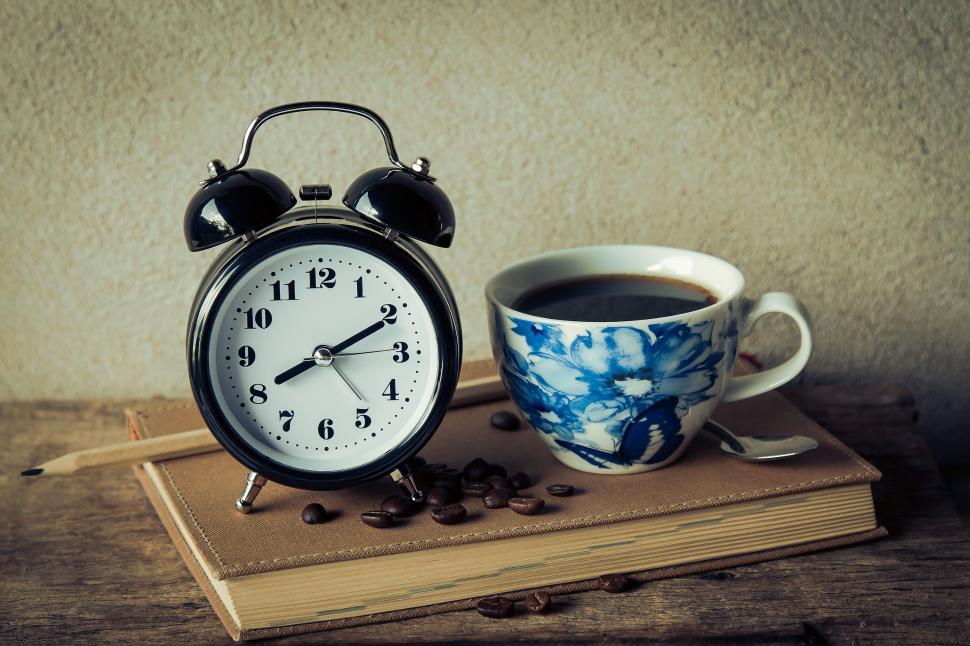 Free Image of A coffee cup and a clock on a book 