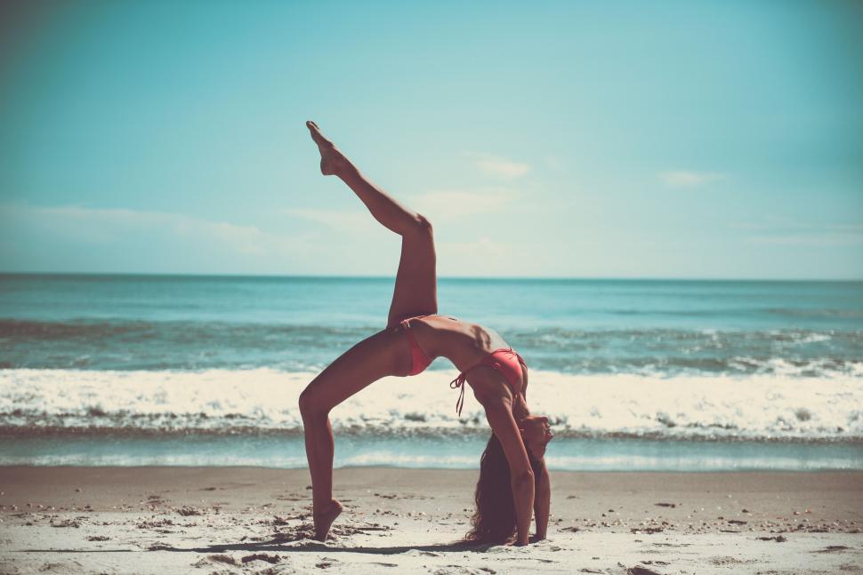 Free Image of A woman doing a back bend on a beach 