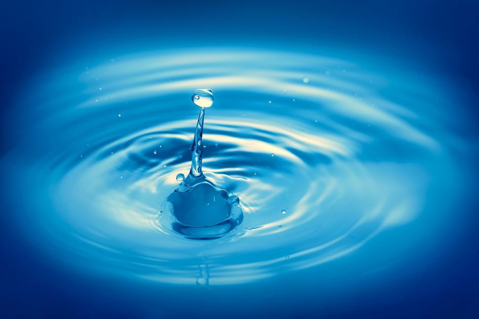Free Image of A water droplet splashing into a blue surface 