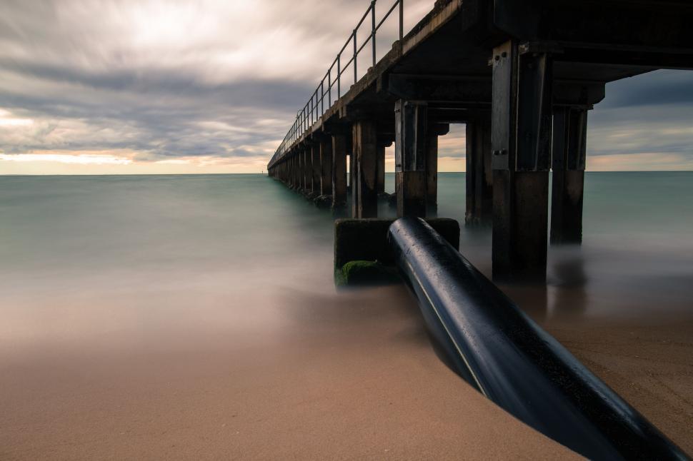 Free Image of A long pier with a pipe on the beach 