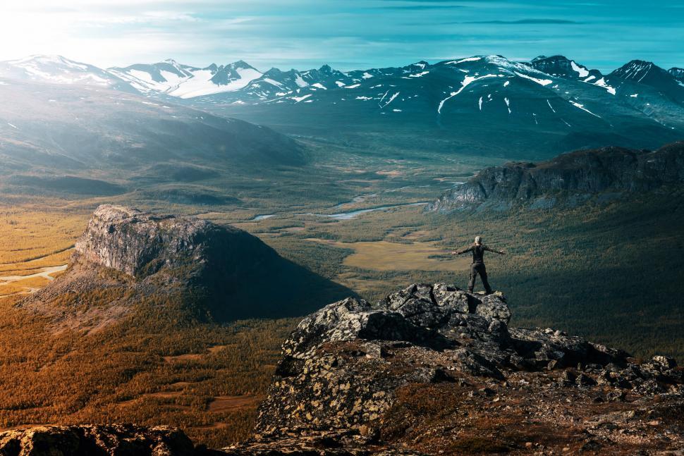 Free Image of A person standing on a rock with mountains in the background 