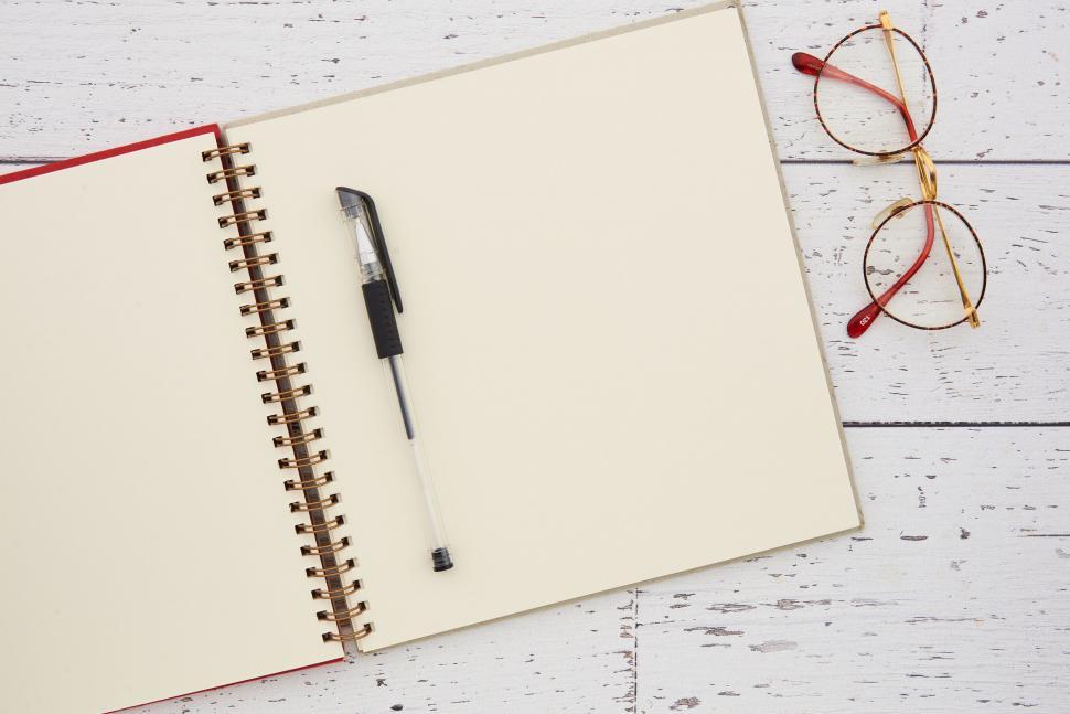 Free Image of A notebook with a pen and glasses on a white surface 