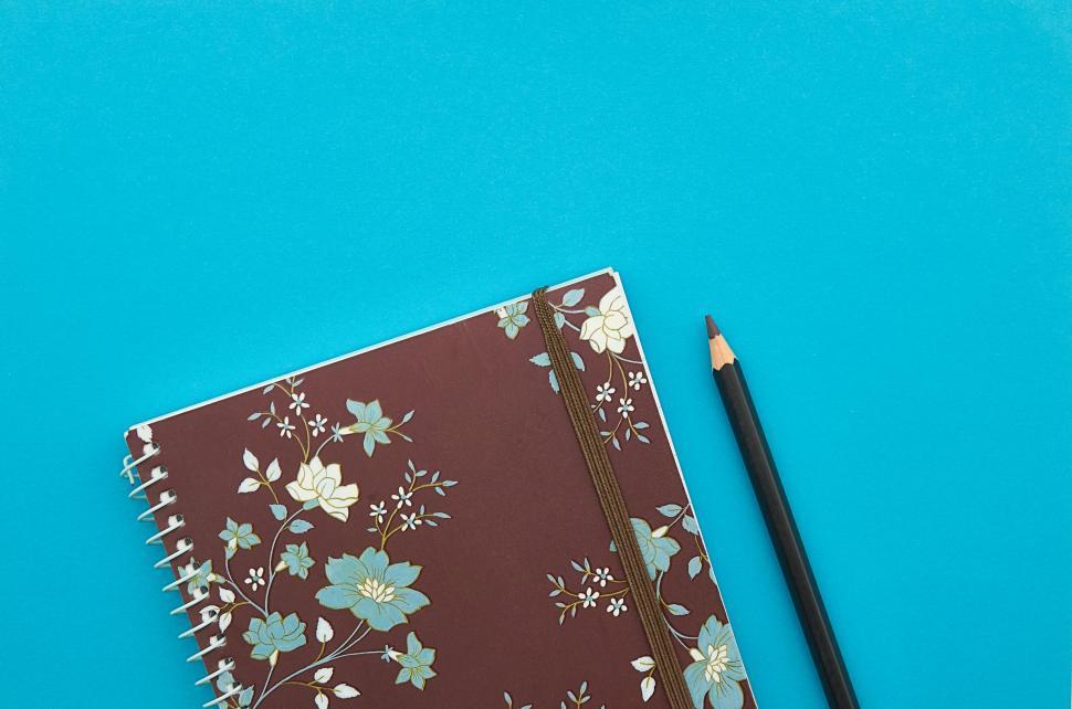 Free Image of A notebook and pencil on a blue background 