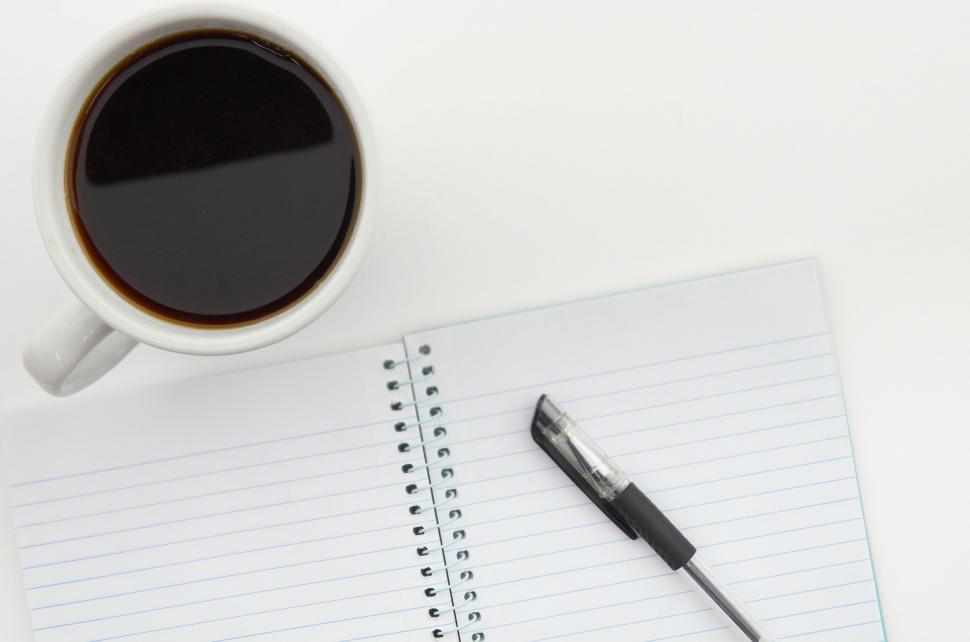 Free Image of A cup of coffee and a pen on a notebook 
