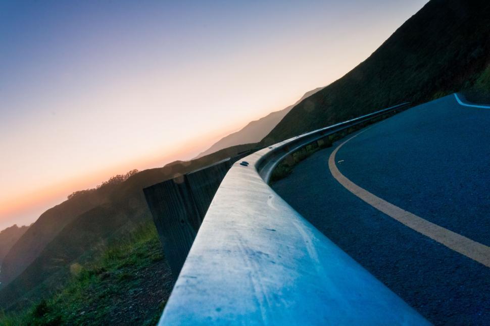 Free Image of A curved road with a mountain in the background 