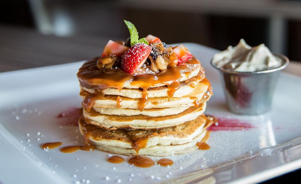 Free Image of A stack of pancakes with strawberries and caramel sauce 