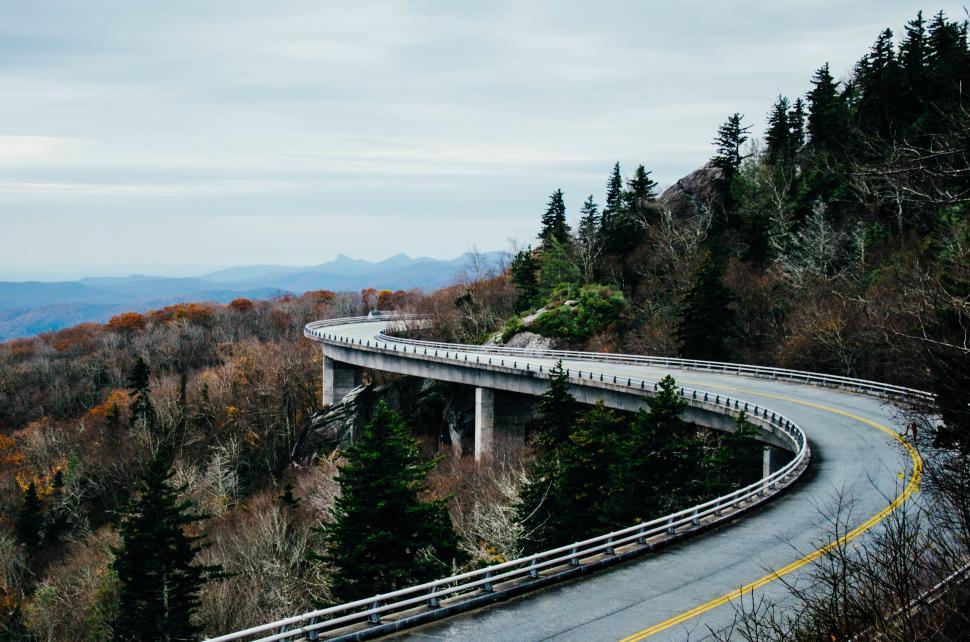 Free Image of A road with a bridge over a hill 
