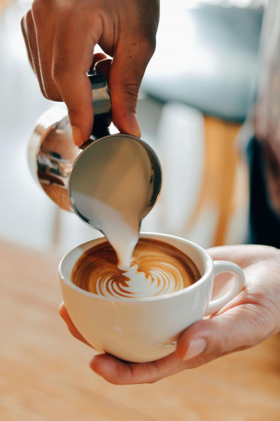 Free Image of A person pouring milk into a cup of coffee 