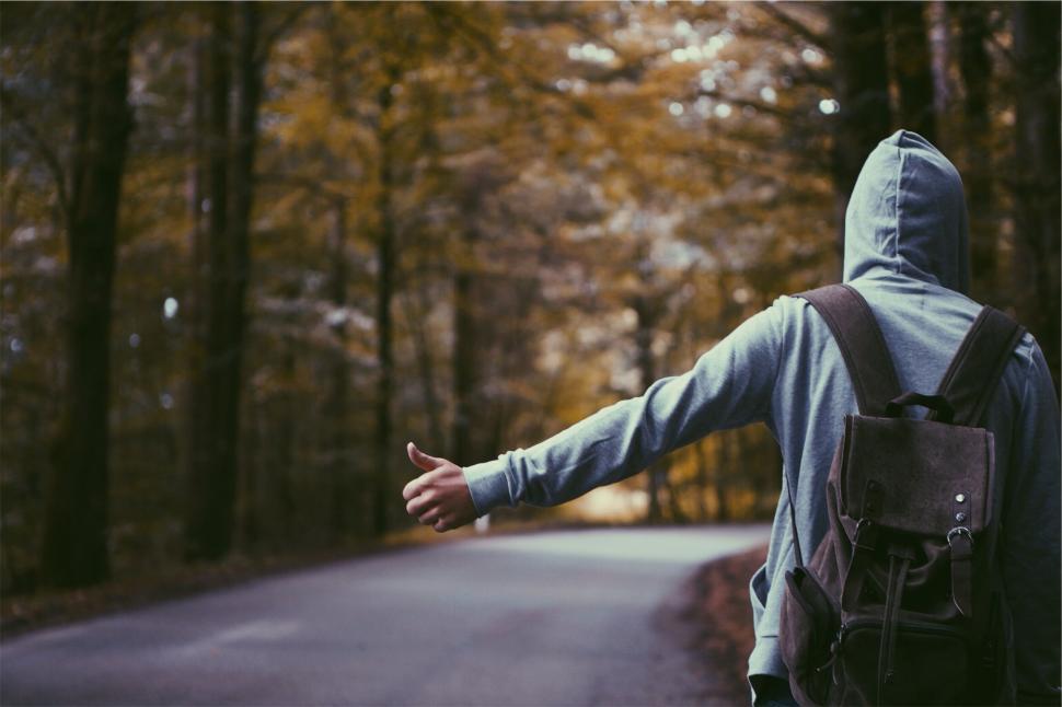 Free Image of A person with a backpack hitchhiking on a road 