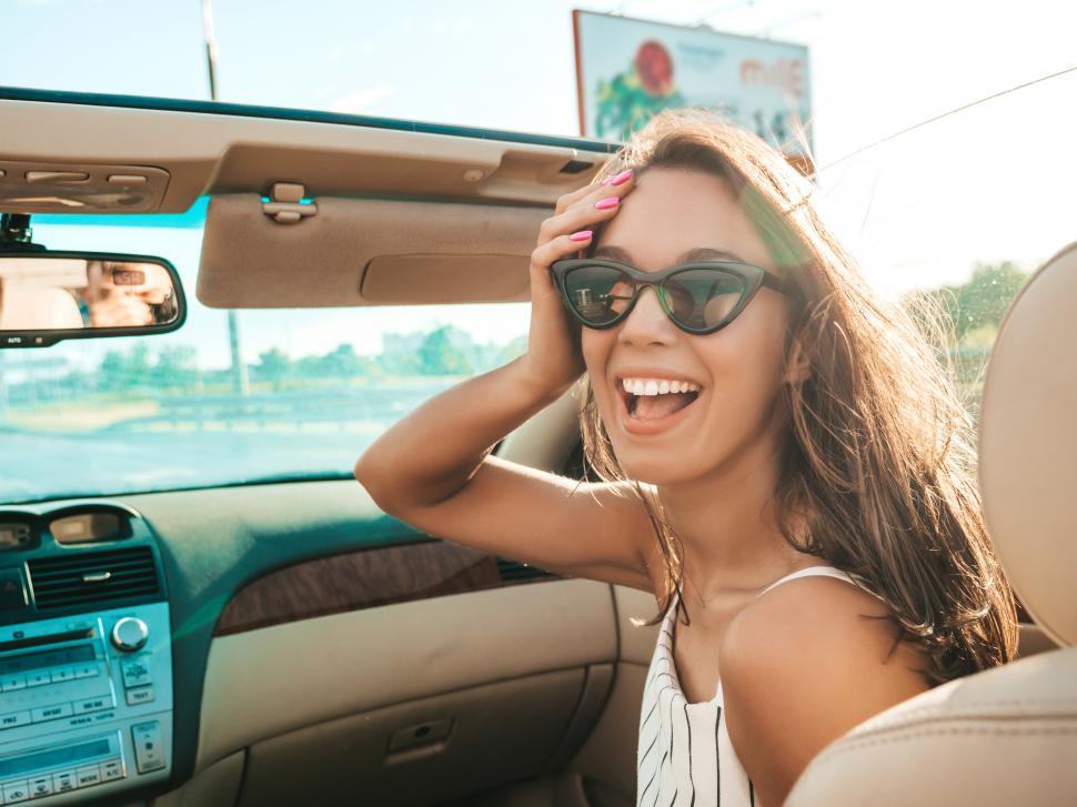 Free Image of A woman in sunglasses in a convertible car 