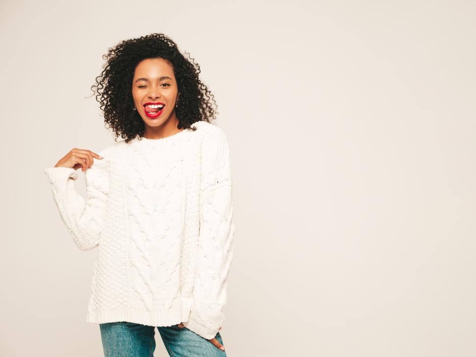 Free Image of A woman with curly hair wearing a white sweater and blue jeans 