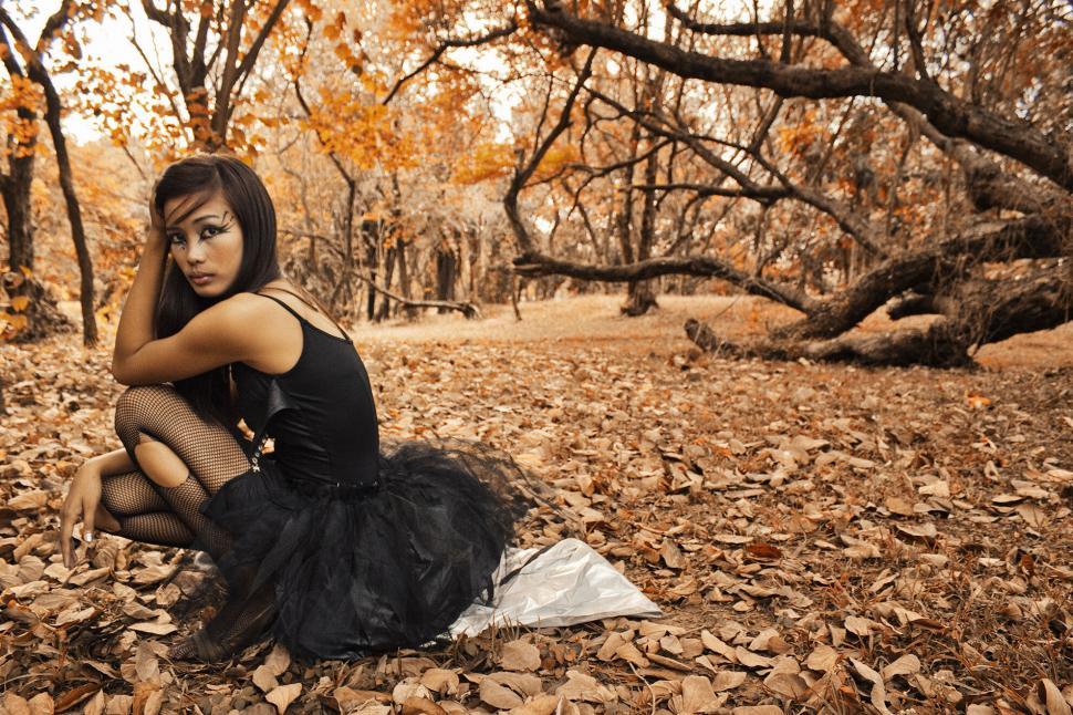Free Image of A woman in a tutu sitting on leaves 