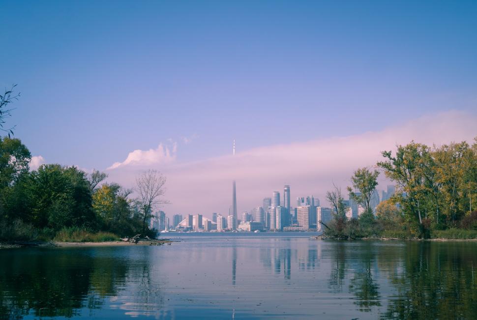 Free Image of A body of water with trees and a city skyline in the distance 