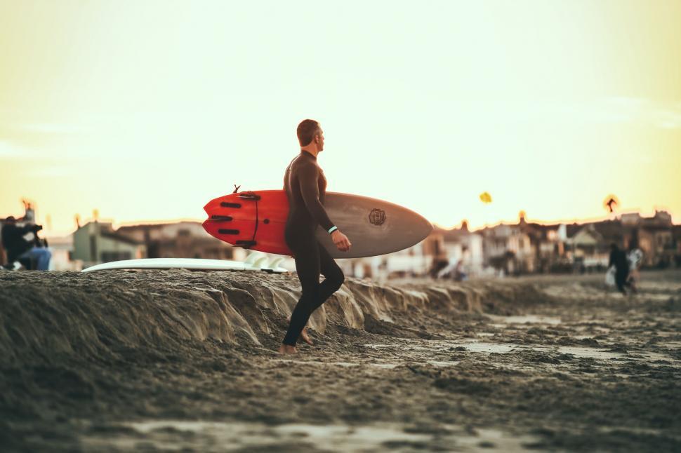 Free Image of A man carrying a surfboard on a beach 