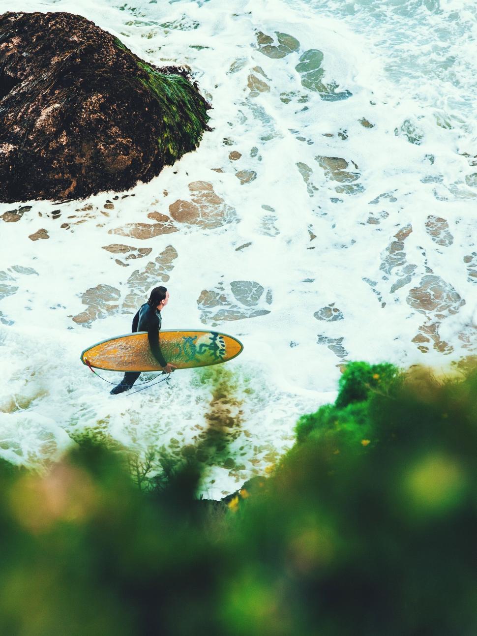 Free Image of A person holding a surfboard in the ocean 