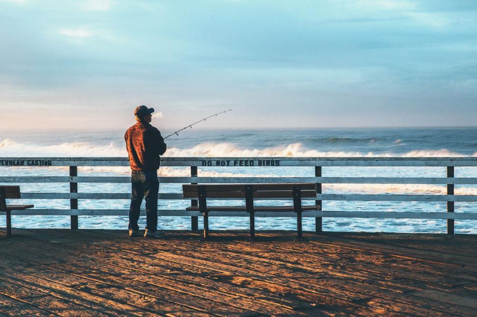 Free Image of A man fishing on a bench 