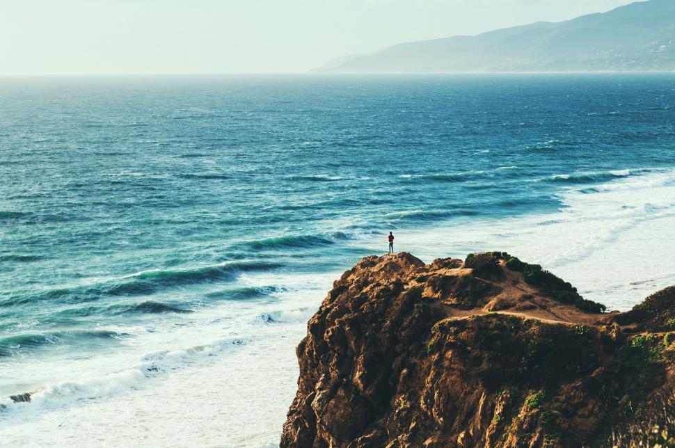 Free Image of A person standing on a cliff overlooking the ocean 