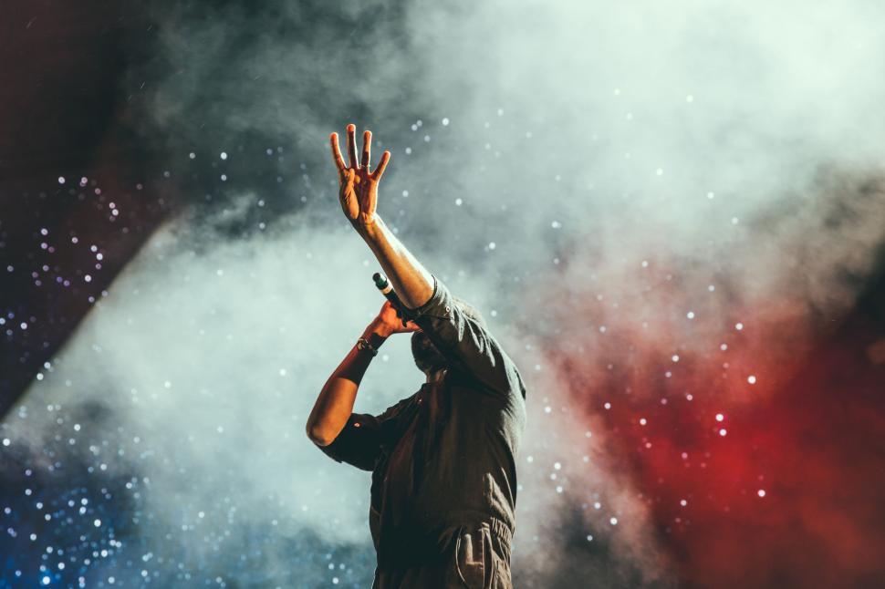 Free Image of A man holding his hand up in front of a smokey background 