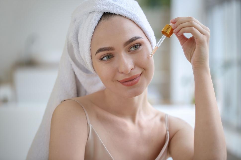 Free Image of A woman with a towel on her head holding a dropper 