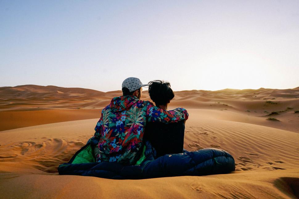 Free Image of Two People Sitting on Top of a Sandy Dune 