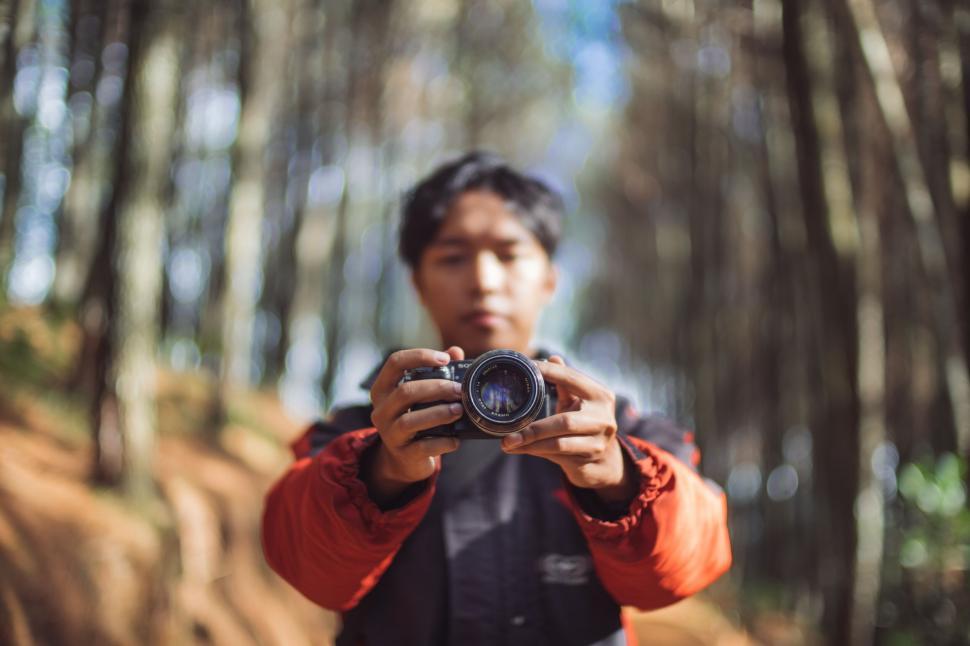 Free Image of A man holding a camera in the woods 