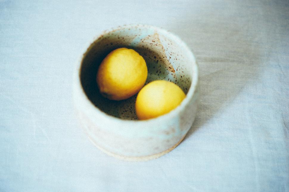 Free Image of Two lemons resting in a pottery bowl 
