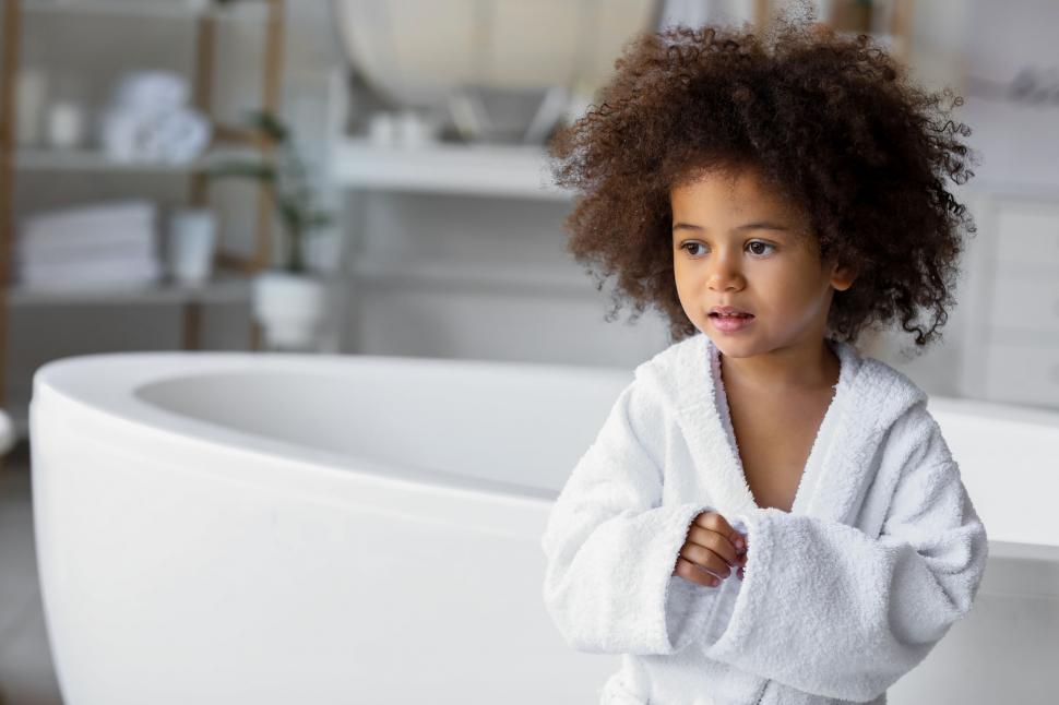 Free Image of Young girl in white bathrobe by tub 