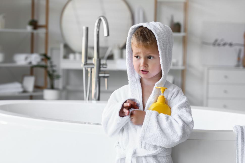 Free Image of Boy in hooded bathrobe holding shampoo 