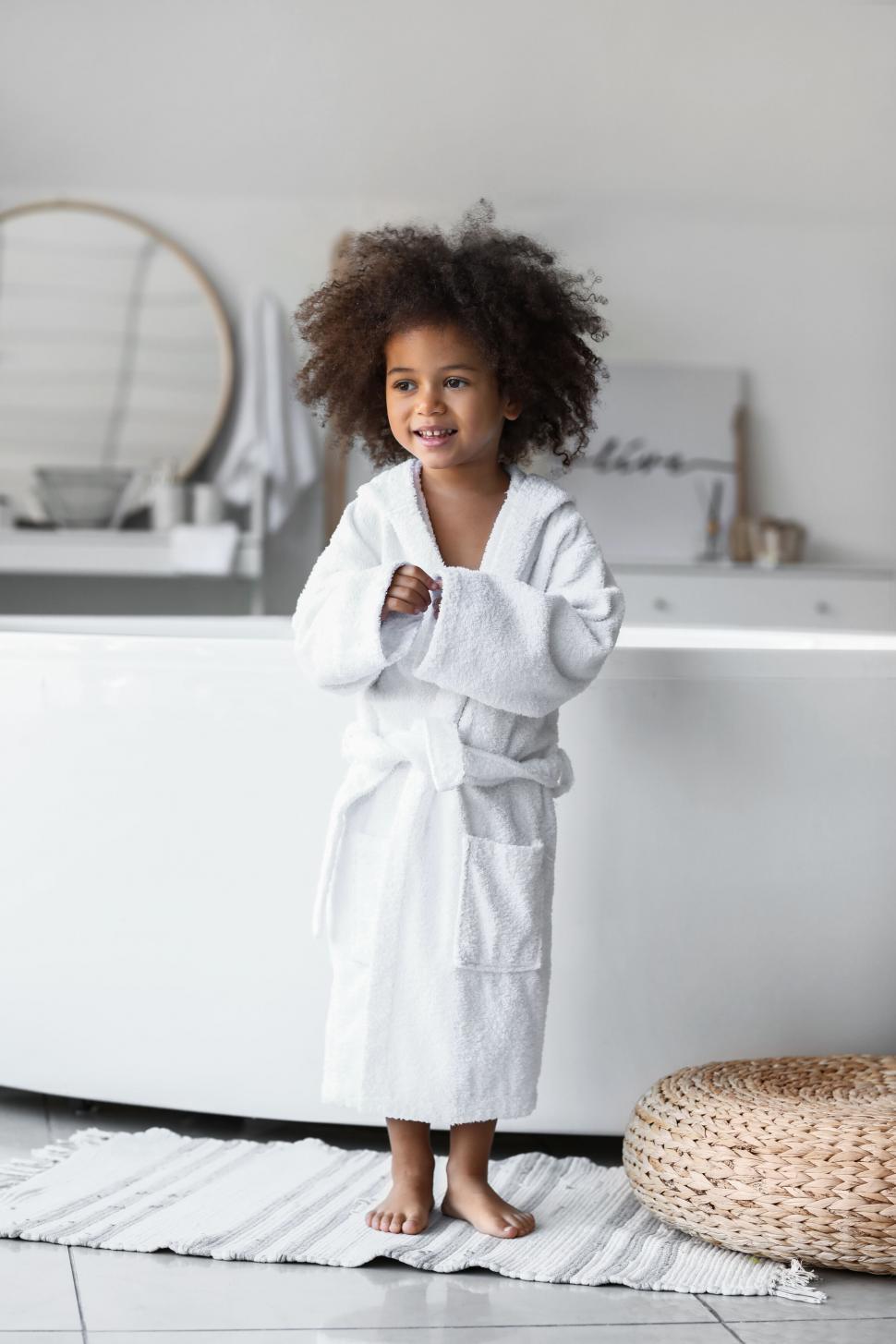 Free Image of Smiling child in white bathrobe standing 