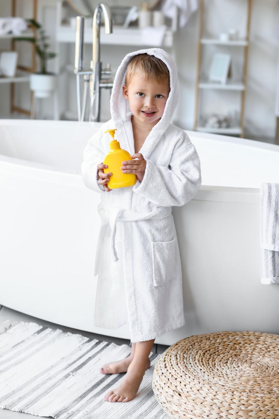 Free Image of Boy in bathrobe holding yellow bottle 