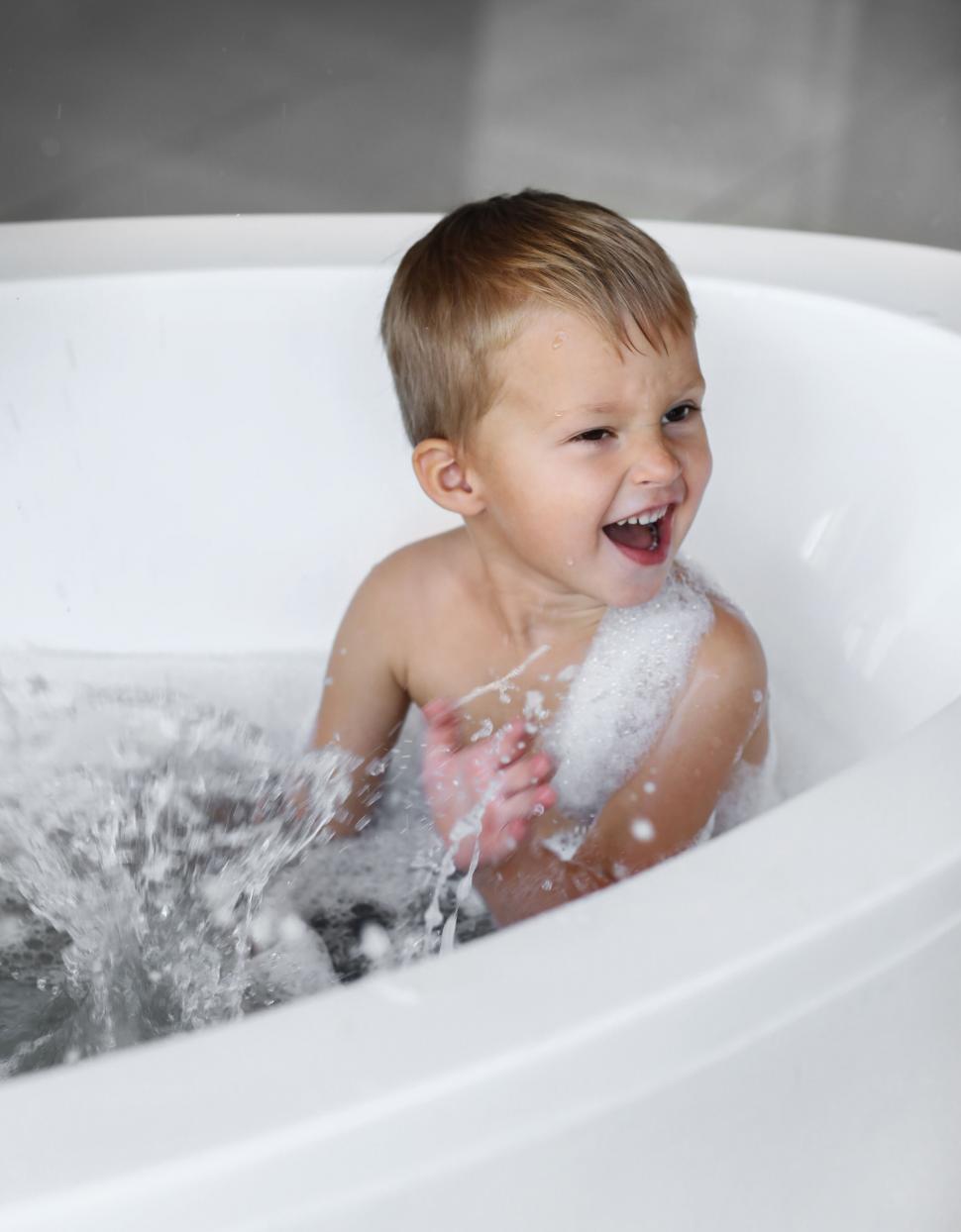 Free Image of Little boy splashing water in the bathtub 