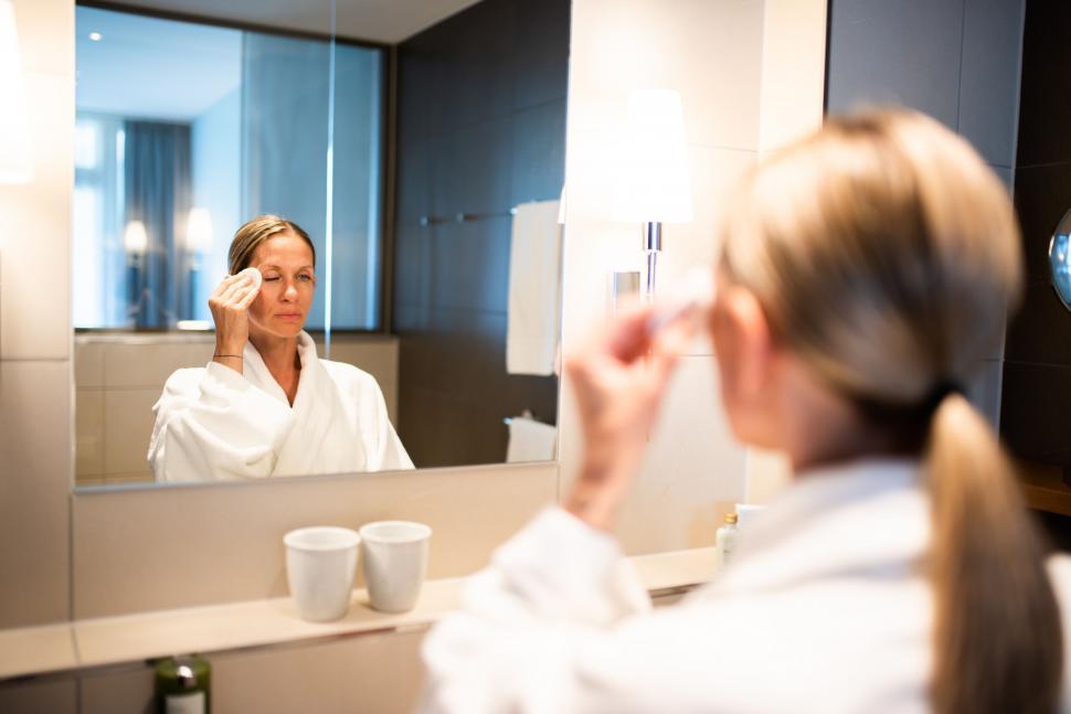 Free Image of Woman applying makeup in bathroom mirror 