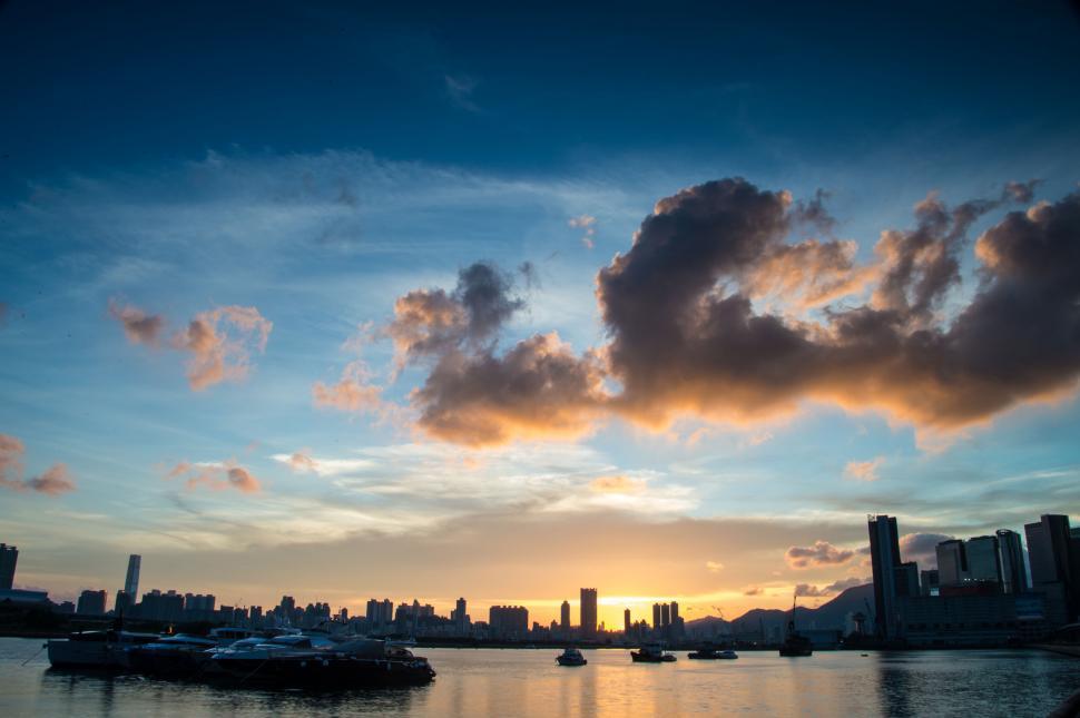 Free Image of Sunset over a city skyline with boats 