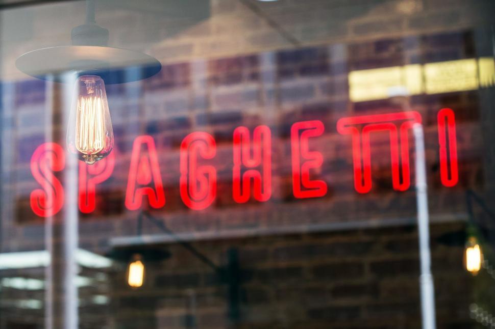 Free Image of Neon sign reading  SPAGHETTI  against brick wall 