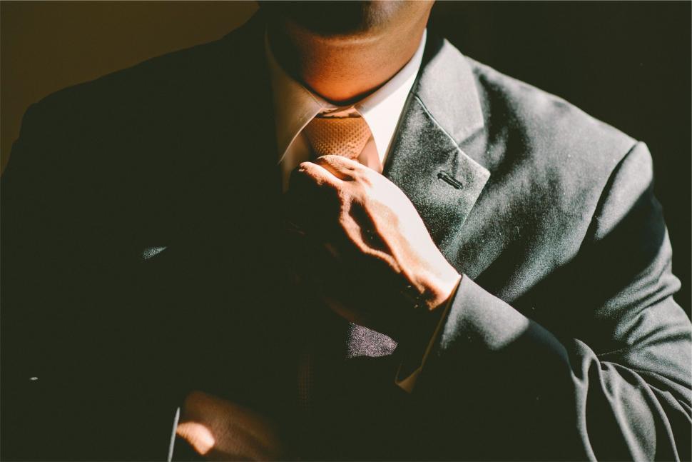 Free Image of Man adjusting tie in sharp business attire 