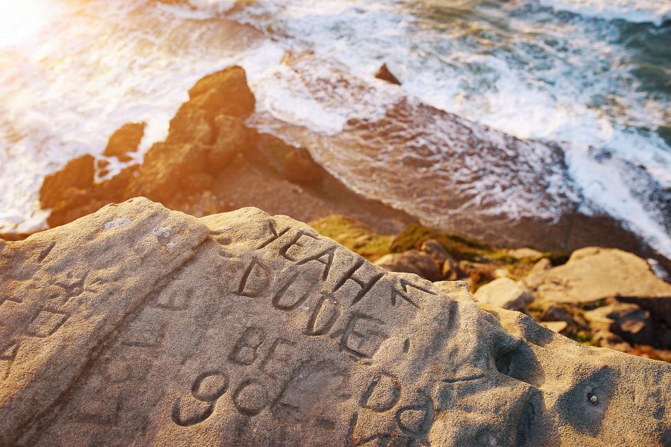 Free Image of Sunset at rocky beach with engraved stone 